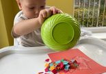 Fotografia Kazika, który wysypuje z miski na kartkę kolorową bibułę.
