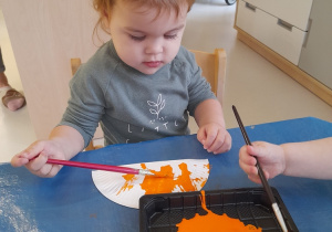 Helenka maluje pomarańczową farbą swój parasol.