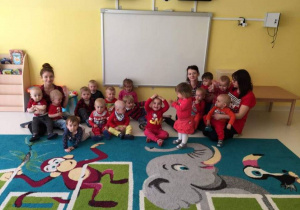 Dzieci i opiekunki ubrane na czerwono pozują do zdjęcia.