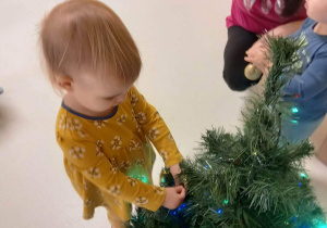 Lilianka zawiesza swoją bombeczkę na świątecznym drzewku.