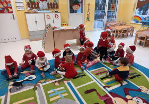Dzieci z grupy Pszczółki siedzące na dywanie podczas oczekiwania na przyjście Świętego Mikołaja.