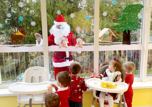 Dzieci z grupy Biedroneczki obserwują przez okno Świętego Mikołaja.