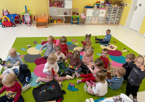 Dzieci z grupy Żabki siedzące na dywanie oglądają różne instrumenty.