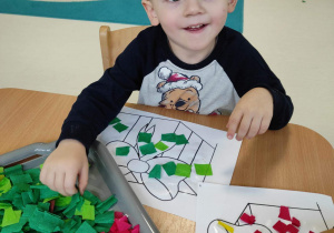 Zdjęcie Hubercika dekorujacego swój prezent zieloną bibułą.
