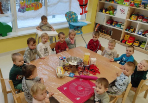 Dzieci z grupy Pszczółki siedzące przy stoliku przed robieniem ciasta na świąteczne pierniczki.