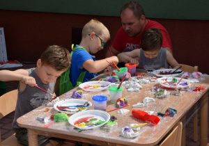 Dzieci malują farbami figurki z gipsu.