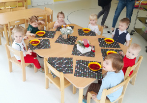 Zdjęcie dzieci pozujących przy wigilijnym obiedzie.