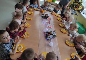 Dzieci przy świątecznym stole jedzą wigilijne drugie danie.