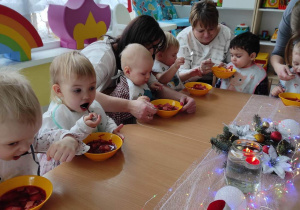 Opiekunki pomagają dzieciom w jedzeniu wigilijnej zupki.