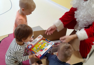 Zdjęcie dzieci podczas otrzymywania prezentów od Mikołaja.
