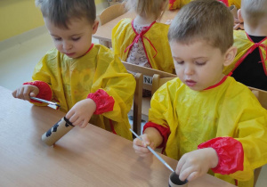 Bartoszek i Oliwierek malują czarną farbą swoje rolki papieru.