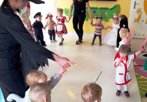 Zdjęcie dzieci tańczących w kole podczas balu kostiumowego.