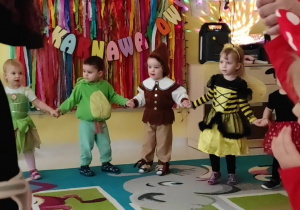 Zdjęcie dzieci trzymających się za rączki podczas tańca w kółku do karnawałowych hitów.