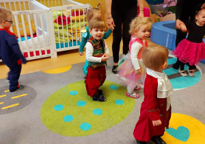 Zdjęcie tańczących uśmiechniętych dzieci na dywanie podczas zabawy.