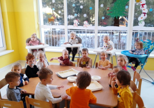 Dzieci z grupy Biedroneczki siedzące przy stole i czekające na rozpoczęcie kulinarnych zajęć.