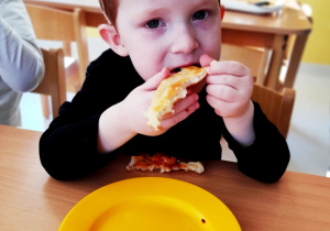 Aleksander z apetytem zjada pyszną pizzę.