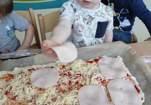 Henio podczas układania plasterków szynki na pizzy.