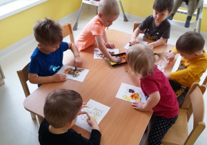 Zdjęcie dzieci pracujących przy stoliku podczas zajęć.