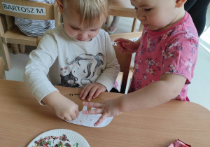 Zdjęcie Lilianki i Alicji wspólnie dekorujących papierowego pączka.