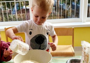 Michał wsypuje przygotowaną mąkę do dużej miski.