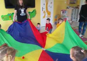 Zabawa dzieci z grupy Biedroneczki kolorową chustą.
