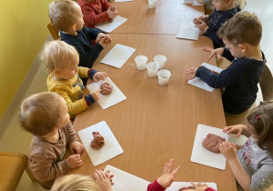 Dzieci z grupy Żabki siedzące przy wspólnym stole podczas pracy plastycznej.