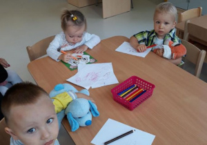 Dzieci z grupy Biedroneczki kolorują kredkami obrazki.