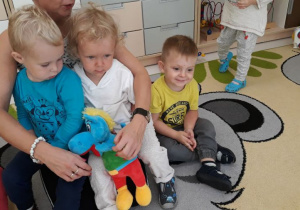 Filip,Szymon oraz Mikołaj siedzą na dywanie i słuchają muzyki.