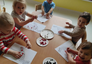 Zdjęcie dzieci ozdabiających przy stoliczku swoje bociany kropkami z plasteliny.
