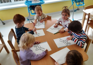 Dzieci z grupy Biedroneczki malują obrazki przy stoliku.