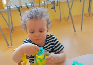 Zdjęcie Stefana wypełniającego buteleczkę zieloną i żółtą bibułą.