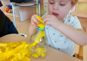 Zdjęcie Miłosza wkładającego żółtą bibułę do swojej buteleczki.