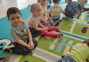 Zdjęcie dzieci siedzących na dywanie podczas zajęć edukacyjnych o wiośnie.
