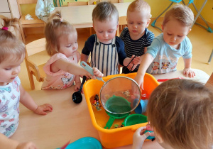 Zdjęcie dzieci próbujących wyłowić pływające w misce z wodą zabawki.