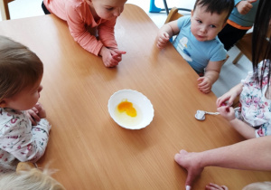 Dzieci oglądają jak wygląda surowe jajko w misce.