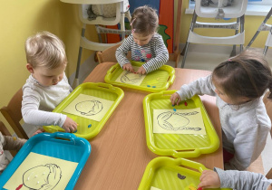 Dzieci z grupy Żabki siedzące przy wspólnym stole podczas zajęć plastycznych.