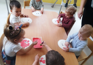 Dzieci z grupy Biedroneczki siedzące przy stole podczas zajęć plastycznych.