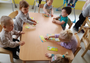 Dzieci siedzące przy stole podczas układania puzzli.