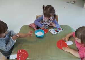 Dziewczynki robią kropeczki farbami na grzybach.