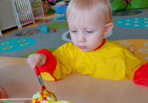 Aleksandra maluje swoje jajeczko żółtą farbą.