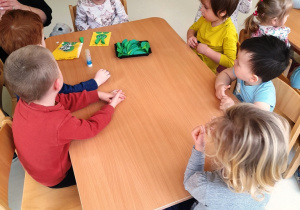 Dzieci przy stolikach wykonują wielkanocne kartki z życzeniami.