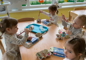 Dzieci z grupy Żabki siedzące przy stoliku w czasie pracy plastycznej.