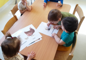 Dzieci przyptrują się różnym obrazkom podczas zajęć.