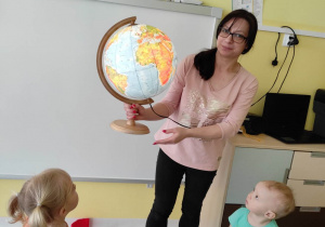 Opiekunka pokazuje maluszkom podświetlany globus.