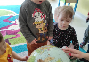 Zdjęcie Szymona przyglądającego się dużemu globusowi.