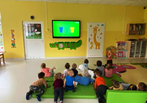 Dzieci oglądające filmik edukacyjny o segregowaniu odpadów.