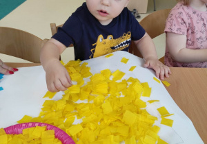 Zdjęcie skupionego Szymona podczas przyklejania żółtych bibułowych kwadracików.