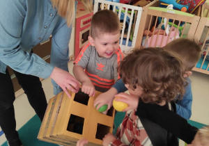 Dzieci wkładają podniesione piłeczki do specjalnie przygotowanego pudełka.