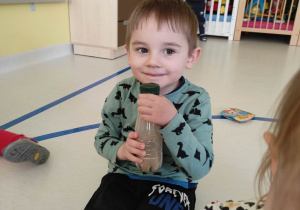 Zdjęcie uśmiechniętego Huberta trzymającego w dłoniach buteleczkę z piaskiem.