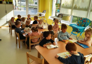 Zdjęcie grupy Biedroneczki siedzącej przy stolikach i oglądającej książki.